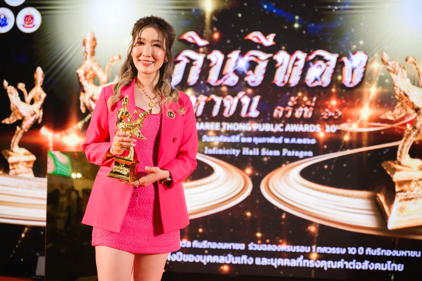 ผู้รับรางวัลถือถ้วยบนเวทีงานกินนรีทองมหาชน